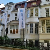 Eine alte Stadtvilla mit zwei Fahnen davor - Geschäftssitz der Inneren Mission