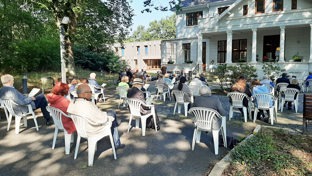 Vor dem Adelenstift in Lesum sitzen Menschen draußen auf Stühlen