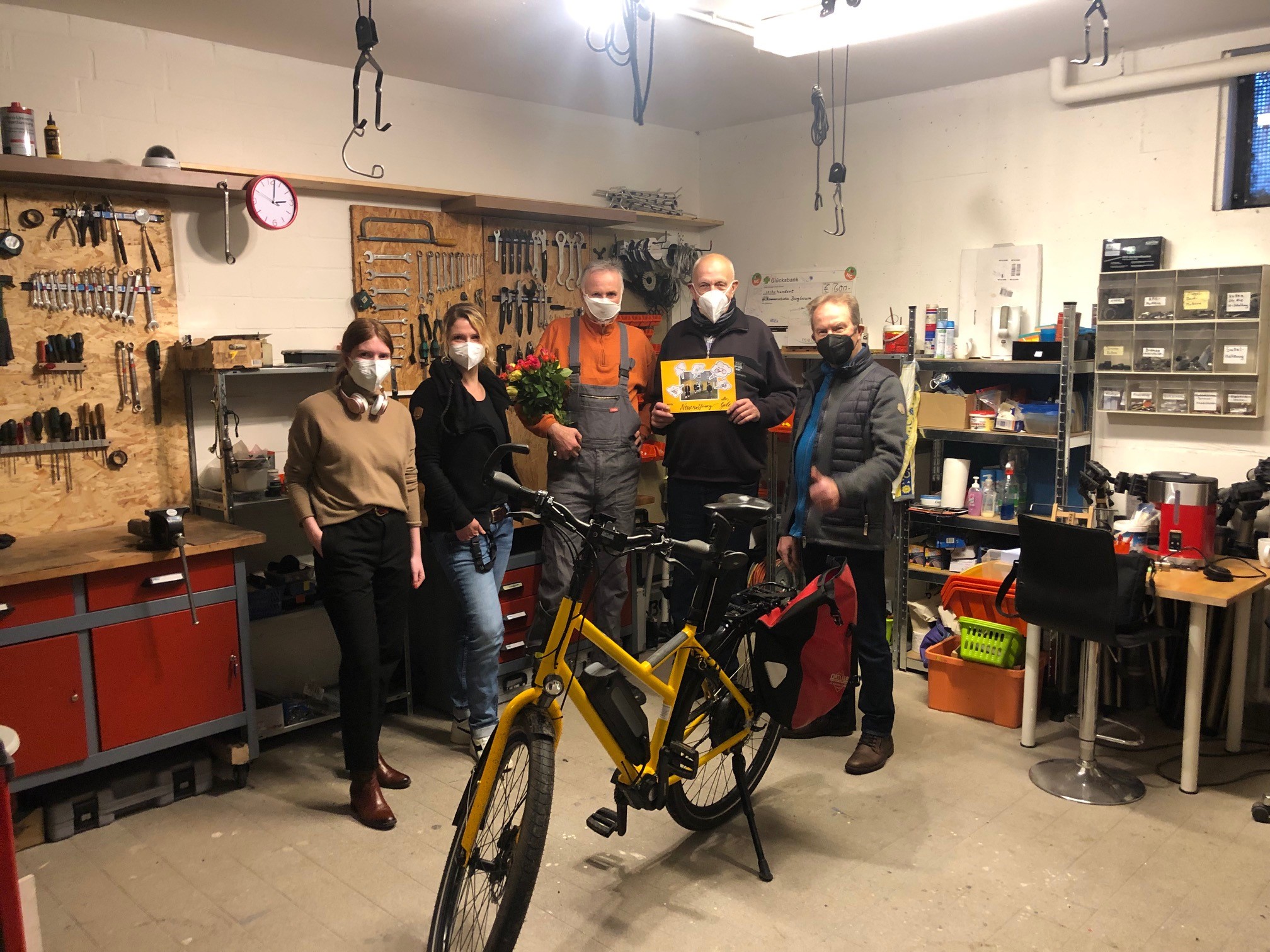 Fahrradwerkstatt und Beratungsbüro arbeiten nun Seite an Seite 2 Frauen und drei Männer stehen in einer Fahrradwerkstatt, vor ihnen steht ein Fahrrad