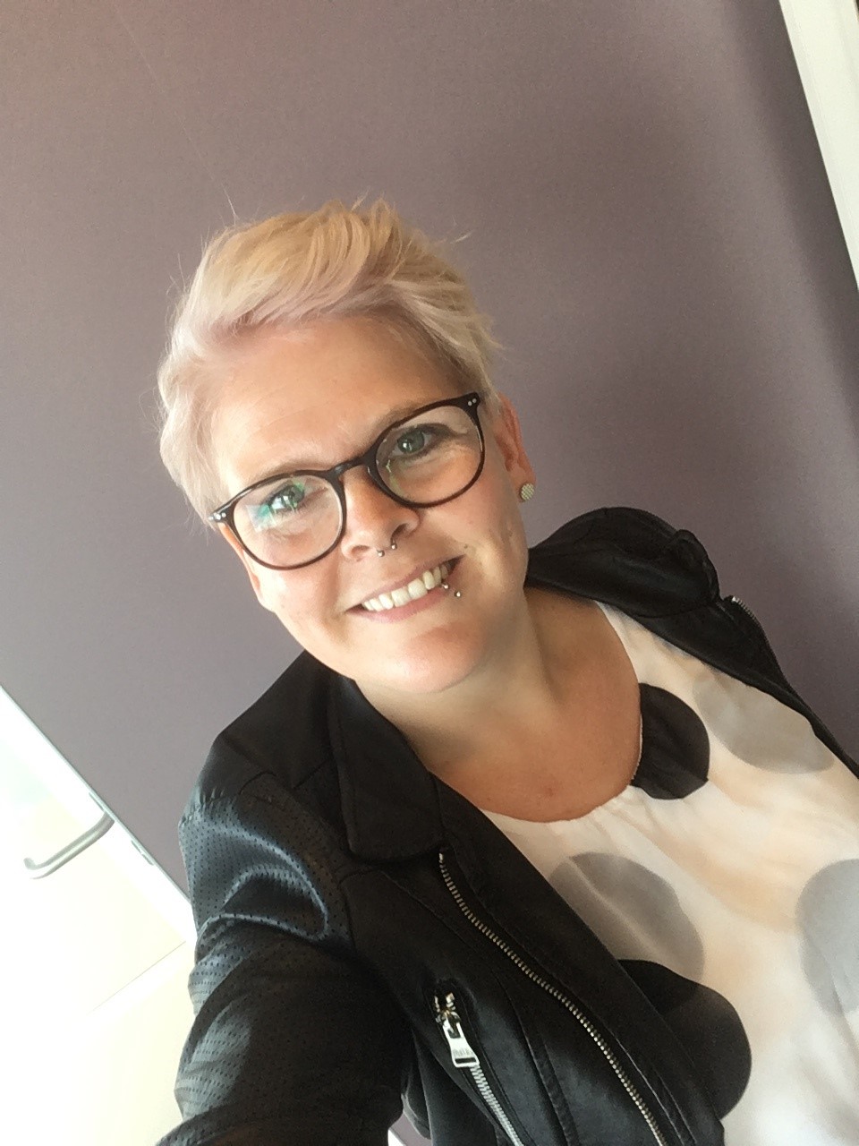 Eileen Bumann Eine Frau mit kurzen blonden Haaren und Brille macht ein Selfie von sich