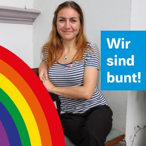 Eine junge Frau sitzt auf einer Bank. Unter ihr läuft ein Regenbogen entlang