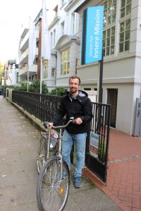 Ein Mann mit einem Fahrrad vor dem Eingangsbreich der Inneren Mission