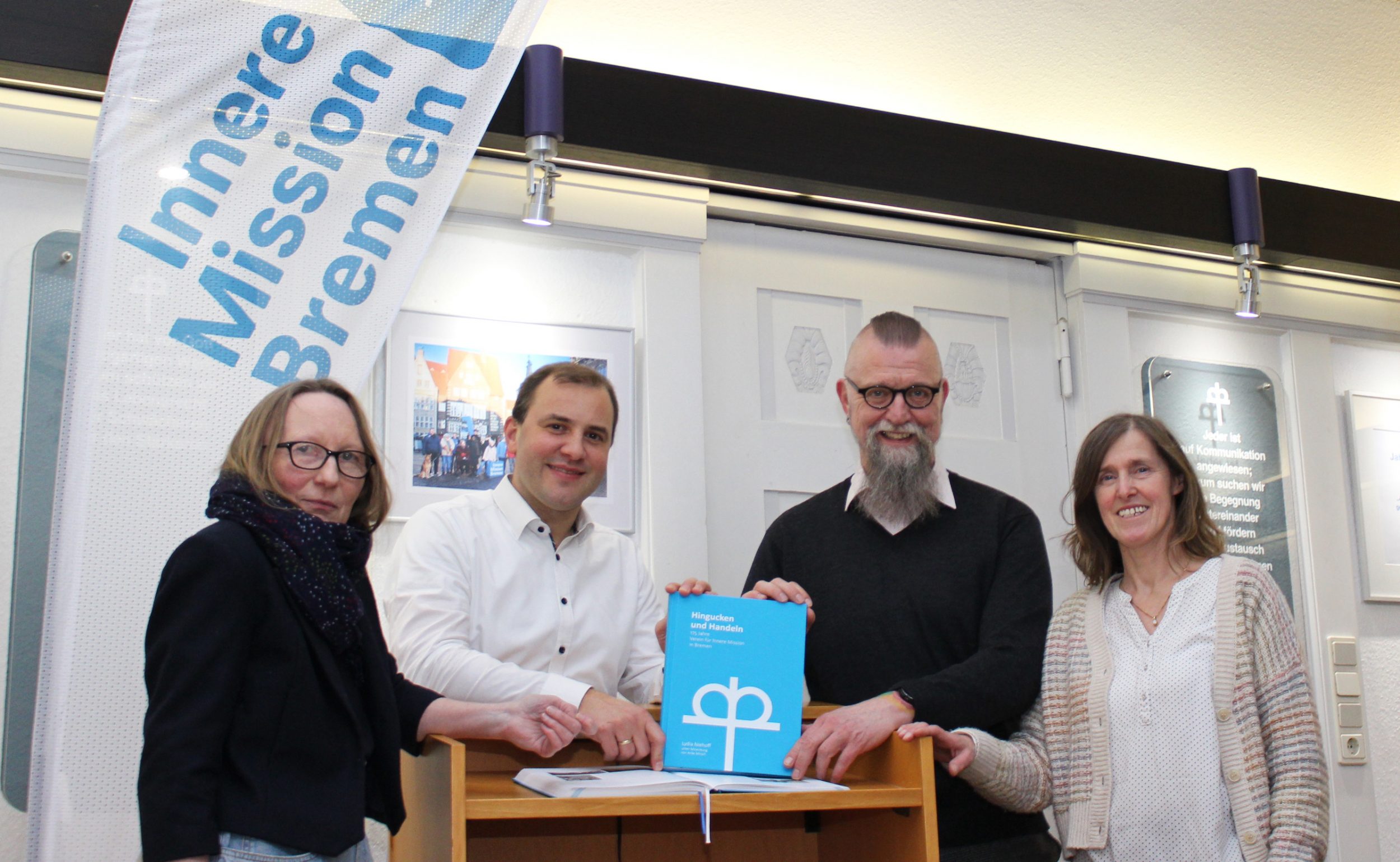 Präsentieren stolz die Chronik (v. l.): Autorin Dr. Lydia Niehoff, Vorstand Thomas Krebs und Dr. Thomas Röhr, Anke Mirsch, die die Autorin unterstützte Zwei Frauen und zwei Männer präsentieren das Buch Chrinik der Inneren Mission Bremen