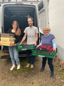 Zwei Frauen und ein Mann mit Kisten mit kleiderspenden in der Hand