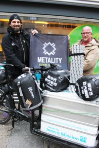 Zwei Männer mit Schlafsäcken vor einem Lastenfahrrad