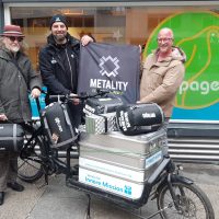 Drei Männer mit Schlafsäcken und einem Lastenfahrrad