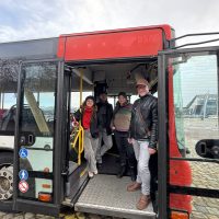 Ein Bus des öffentlichen Nachverkehrs. Im Fahrerbereich stehen zwei Männer und zwei Frauen