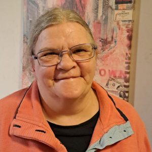 Eine Frau mit orangenem Pullover und Brille