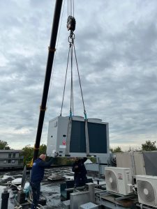Ein Kran hebt eine Wärmepumpe auf Dach